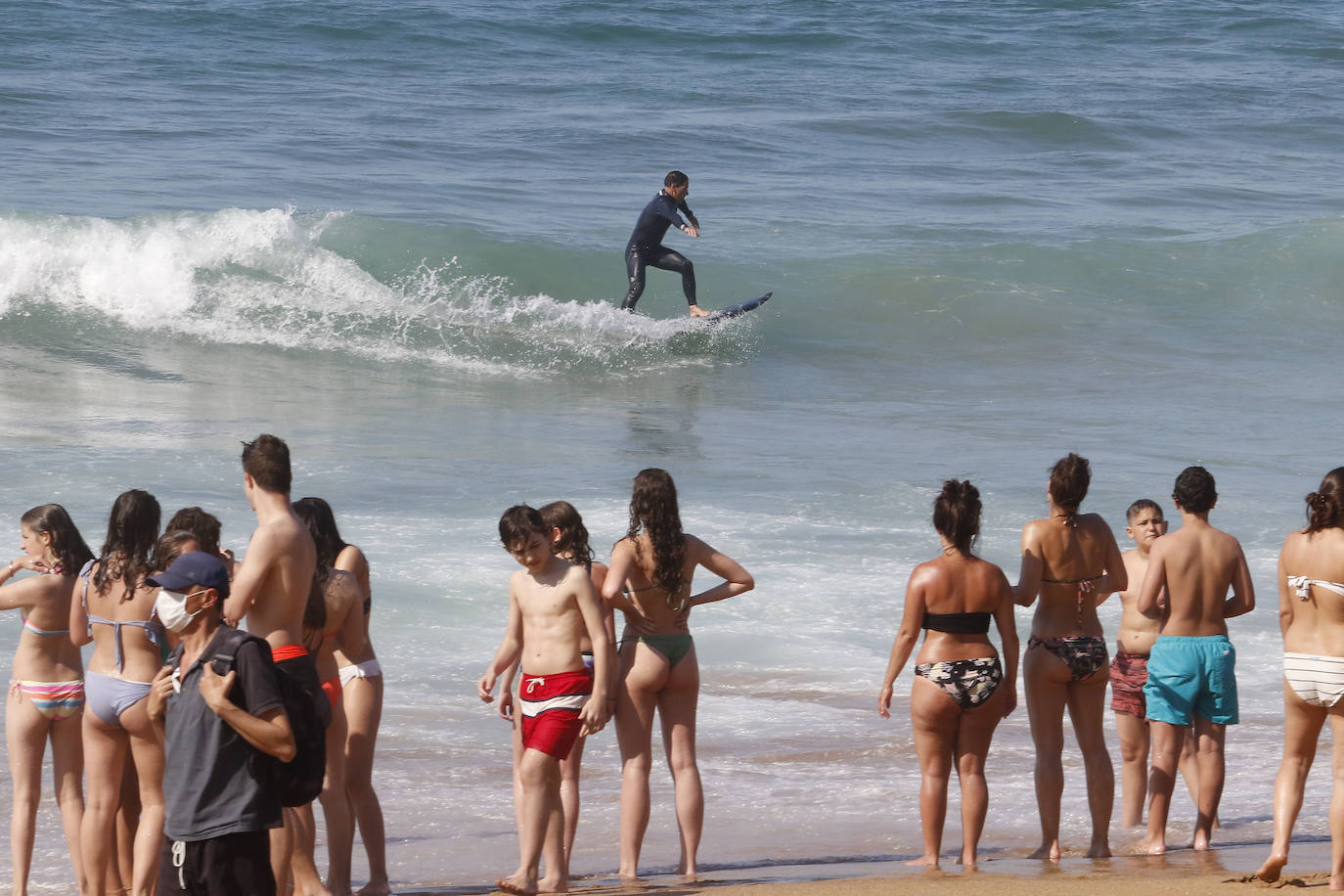 Los arenales gijoneses han vuelto este martes a llenarse de gente que ha querido pasar una nueva jornada de intenso calor tumbado en la arena o refrescándose en el agua.