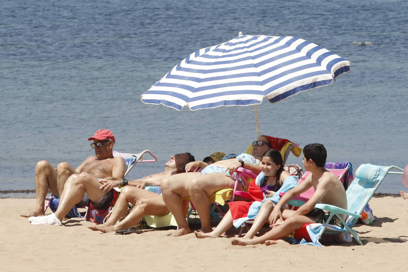 Los arenales gijoneses han vuelto este martes a llenarse de gente que ha querido pasar una nueva jornada de intenso calor tumbado en la arena o refrescándose en el agua.