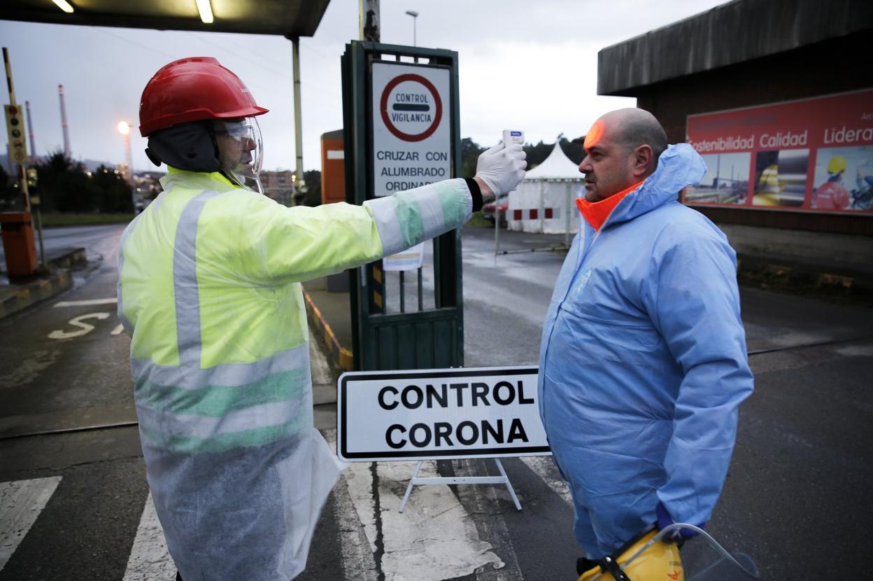 Un operario controla la temperatura de un trabajador en el acceso a la planta de ArcelorMittal en en Avilés. 