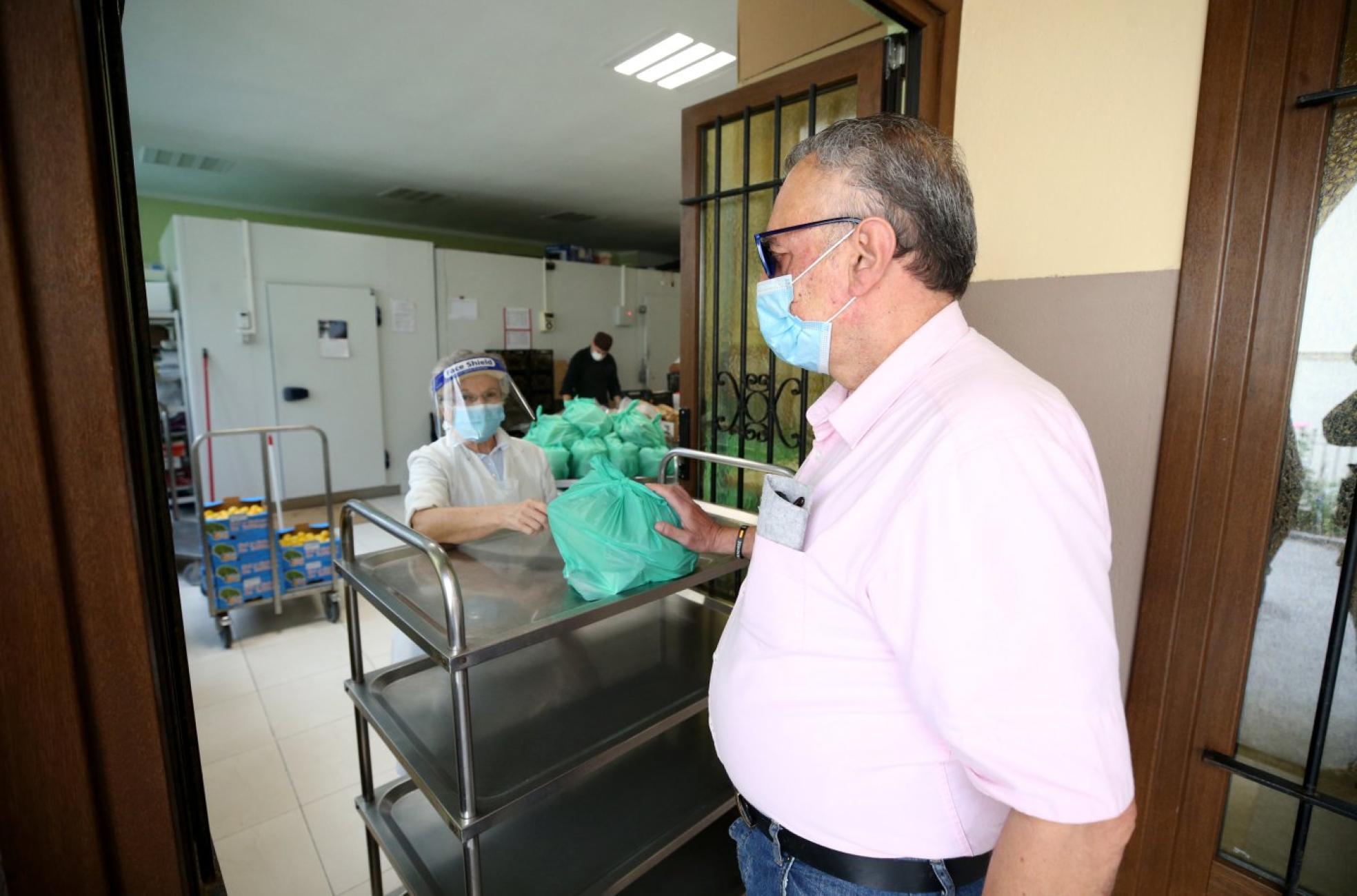 Carlos Díez recoge su comida en el mostrador de la Cocina Económica de Oviedo. 