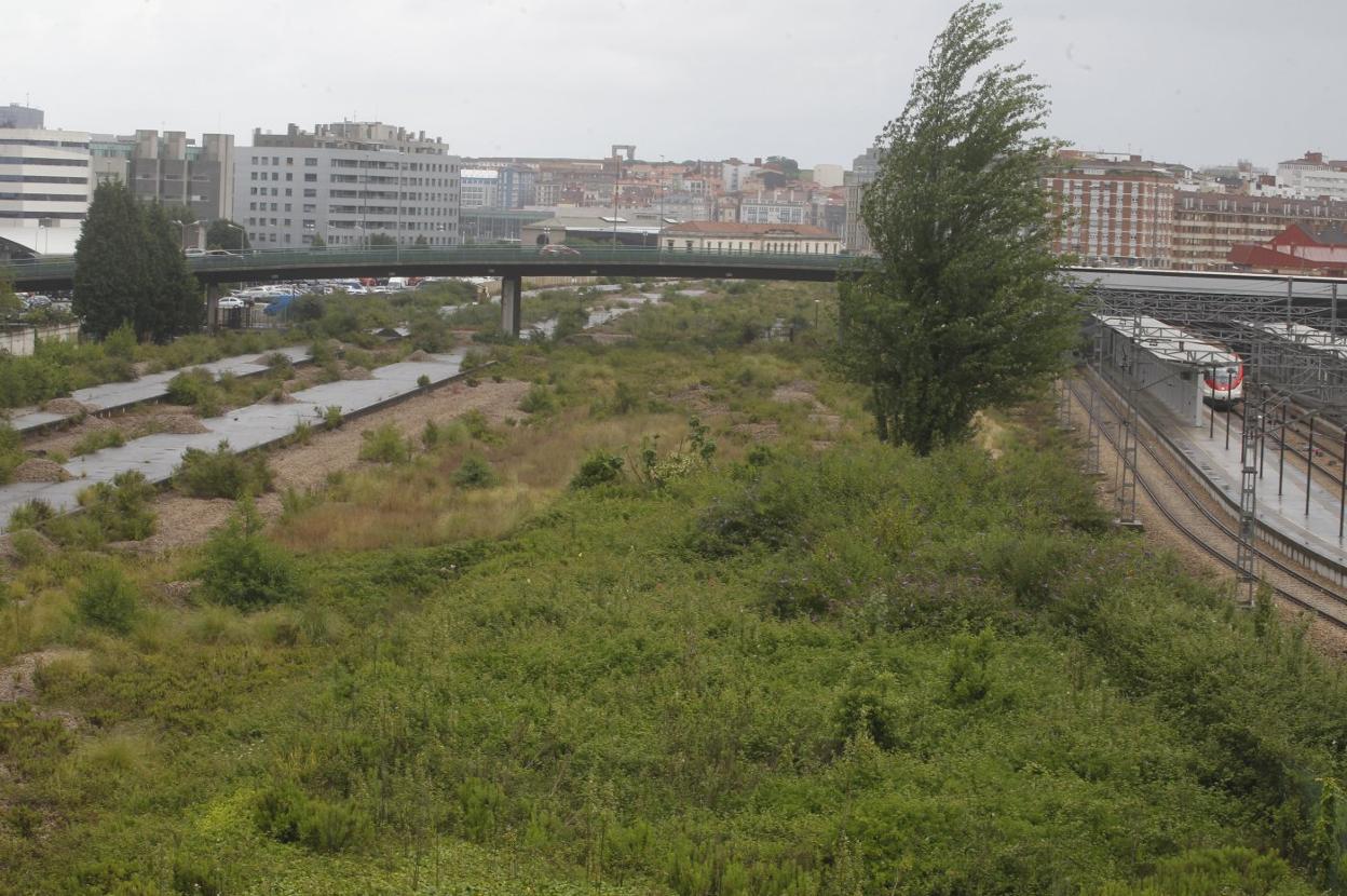 A la derecha, un tren en la estación provisional de Sanz Crespo. Cubierta de vegetación y con viejos andenes, el espacio reservado para la estación intermodal si se hace en Moreda. Al fondo, el Museo del Ferrocarril, junto al que se pactó llevar la instalación. 