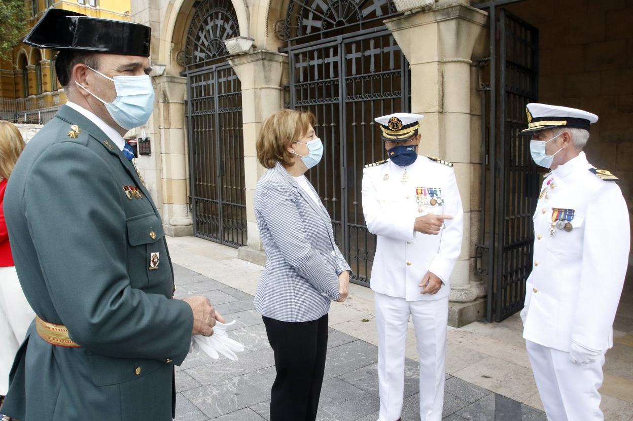 El capitán de la Comandancia Naval de Gijón, Carlos Orueta Lueje (segundo por la derecha), conversa con la delegada del Gobierno, Delia Losa, minutos antes de la misa en San Pedro. 