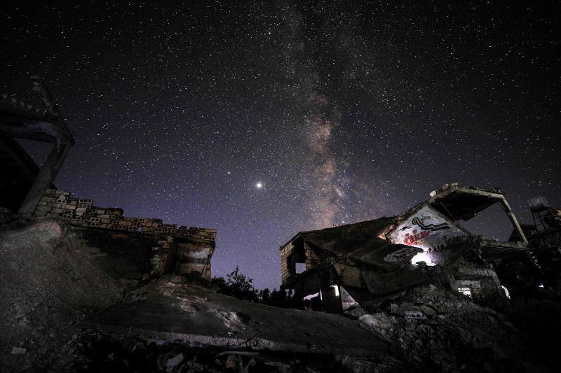 Parece que el mundo se detiene al observar el cielo estrellado de Idlib (Siria). Sin embargo, basta con bajar un poco la mirada para darse cuenta de la realidad: edificios destruidos por una guerra que comenzó hace más de nueve años y que parece no tener fin, un campamento para sirios desplazados, un parque de atracciones abandonado y combatientes a lo largo de la primera línea con las fuerzas gubernamentales. Así son las noches en la provincia de Idlib, controlada por los rebeldes sirios. 