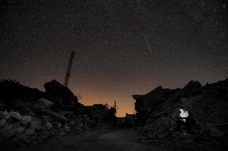 Parece que el mundo se detiene al observar el cielo estrellado de Idlib (Siria). Sin embargo, basta con bajar un poco la mirada para darse cuenta de la realidad: edificios destruidos por una guerra que comenzó hace más de nueve años y que parece no tener fin, un campamento para sirios desplazados, un parque de atracciones abandonado y combatientes a lo largo de la primera línea con las fuerzas gubernamentales. Así son las noches en la provincia de Idlib, controlada por los rebeldes sirios. 