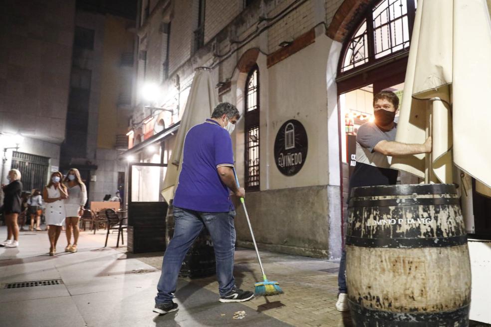Recogida en los bares mientras la gente sigue en la calle en Gijón.