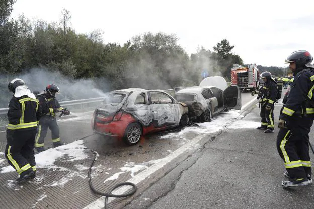 Los bomberos sofocan las llamas que calcinaron los dos vehículos. 