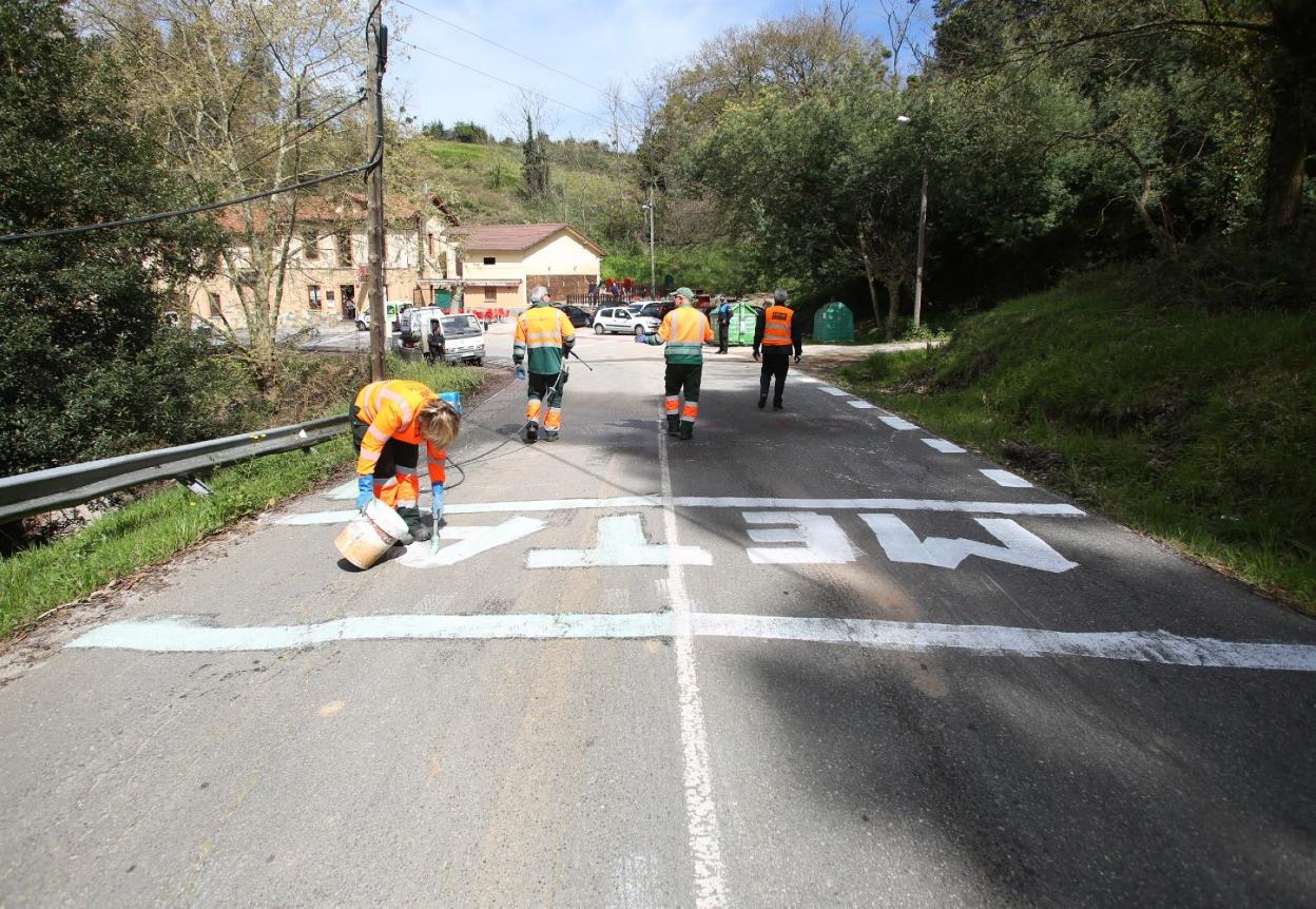 Operarios limpian un pintada de meta en Somió. 