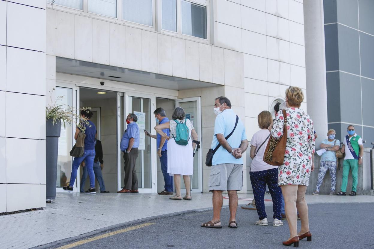 Varias personas aguardan su turno en una cola ante la entrada principal del Hospital Universitario de Cabueñes. 
