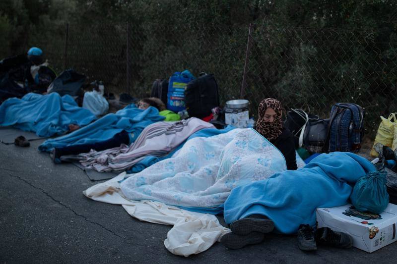 Miles de personas pasan la noche a la intemperie en los alrededores del devastado campo de refugiados de Moria (Lesbos), el más grande de Grecia, a la espera de ser trasladados. Las carreteras que rodean el campo, en el que malvivían 13.000 personas, están repletas de familias que con lo poco que les ha quedado se han instalado en la calzada o en alguna cercana al campo que no ha sido destruida por el incendio del martes por la noche; un incendio que comenzó simultáneamente en varios puntos del campo, poco después de que las autoridades comunicaran a 35 personas que habían dado positivo de covid-19 y que debían ser aisladas. 