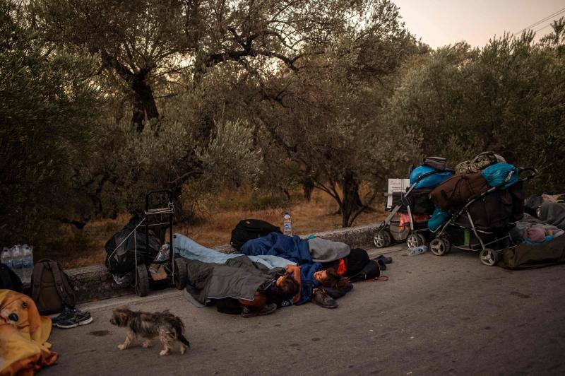 Miles de personas pasan la noche a la intemperie en los alrededores del devastado campo de refugiados de Moria (Lesbos), el más grande de Grecia, a la espera de ser trasladados. Las carreteras que rodean el campo, en el que malvivían 13.000 personas, están repletas de familias que con lo poco que les ha quedado se han instalado en la calzada o en alguna cercana al campo que no ha sido destruida por el incendio del martes por la noche; un incendio que comenzó simultáneamente en varios puntos del campo, poco después de que las autoridades comunicaran a 35 personas que habían dado positivo de covid-19 y que debían ser aisladas. 