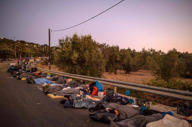 Miles de personas pasan la noche a la intemperie en los alrededores del devastado campo de refugiados de Moria (Lesbos), el más grande de Grecia, a la espera de ser trasladados. Las carreteras que rodean el campo, en el que malvivían 13.000 personas, están repletas de familias que con lo poco que les ha quedado se han instalado en la calzada o en alguna cercana al campo que no ha sido destruida por el incendio del martes por la noche; un incendio que comenzó simultáneamente en varios puntos del campo, poco después de que las autoridades comunicaran a 35 personas que habían dado positivo de covid-19 y que debían ser aisladas. 