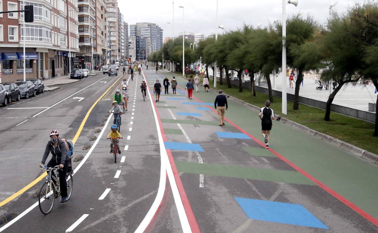 Ciclistas y peatones en el paseo del Muro de Gijón.