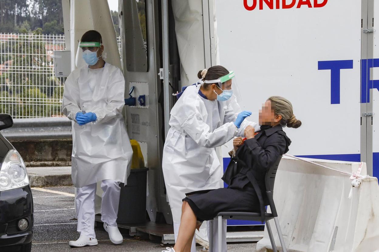 Dos sanitarios atienden a una mujer en el autocovid habilitado ante el Hospital de Cabueñes. 