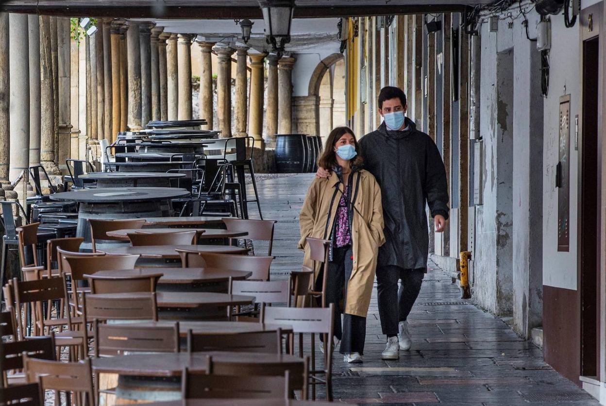 Una pareja pasea por la calle Galiana de Avilés, con las terrazas vacías.