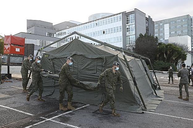 Los militares, durante la instalación de las tiendas de la unidad de triaje en el aparcamiento del Hospital de Cabueñes. 