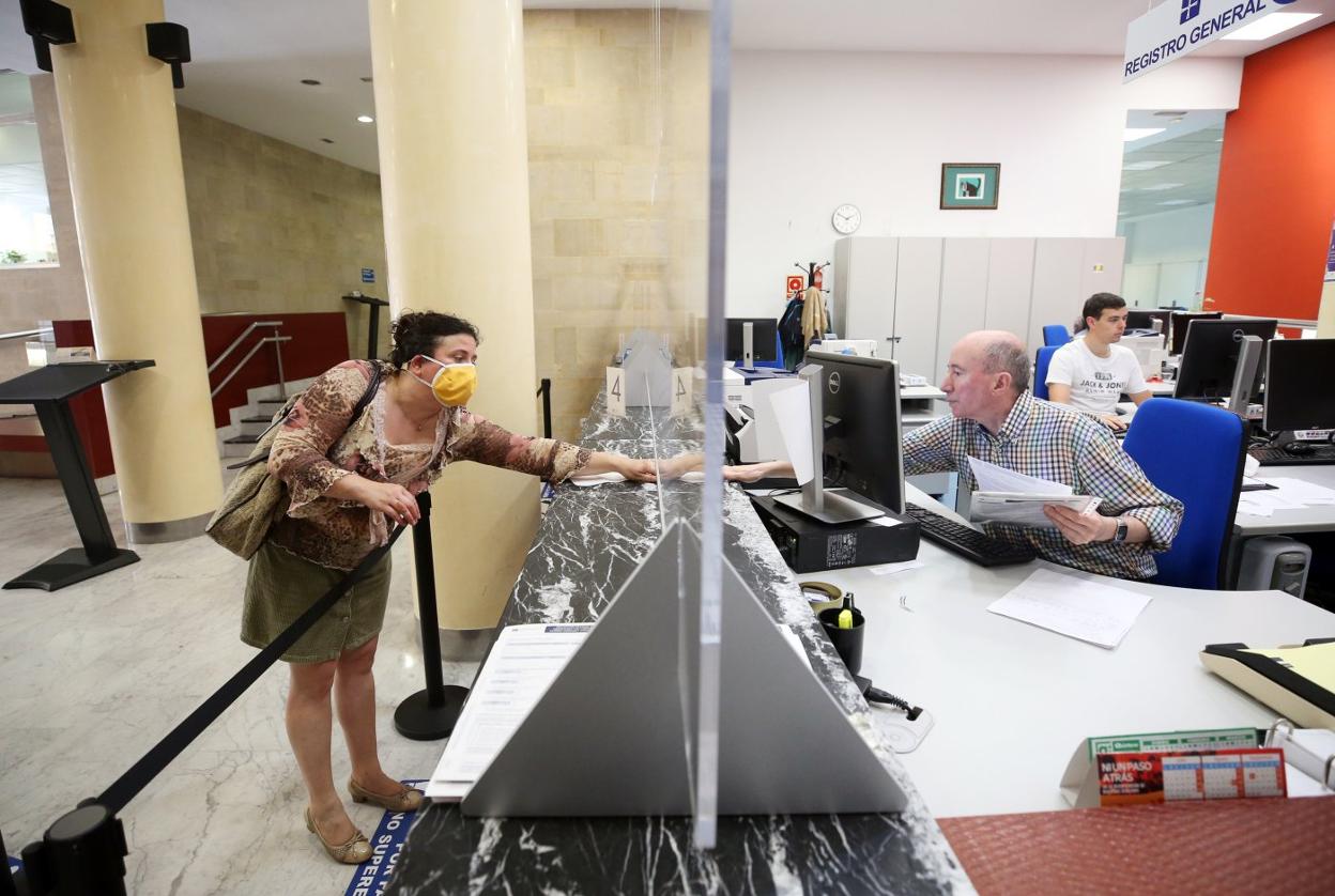 Una mujer, haciendo un trámite en el Registro del Ayuntamiento de Oviedo, con pantallas protectoras. 