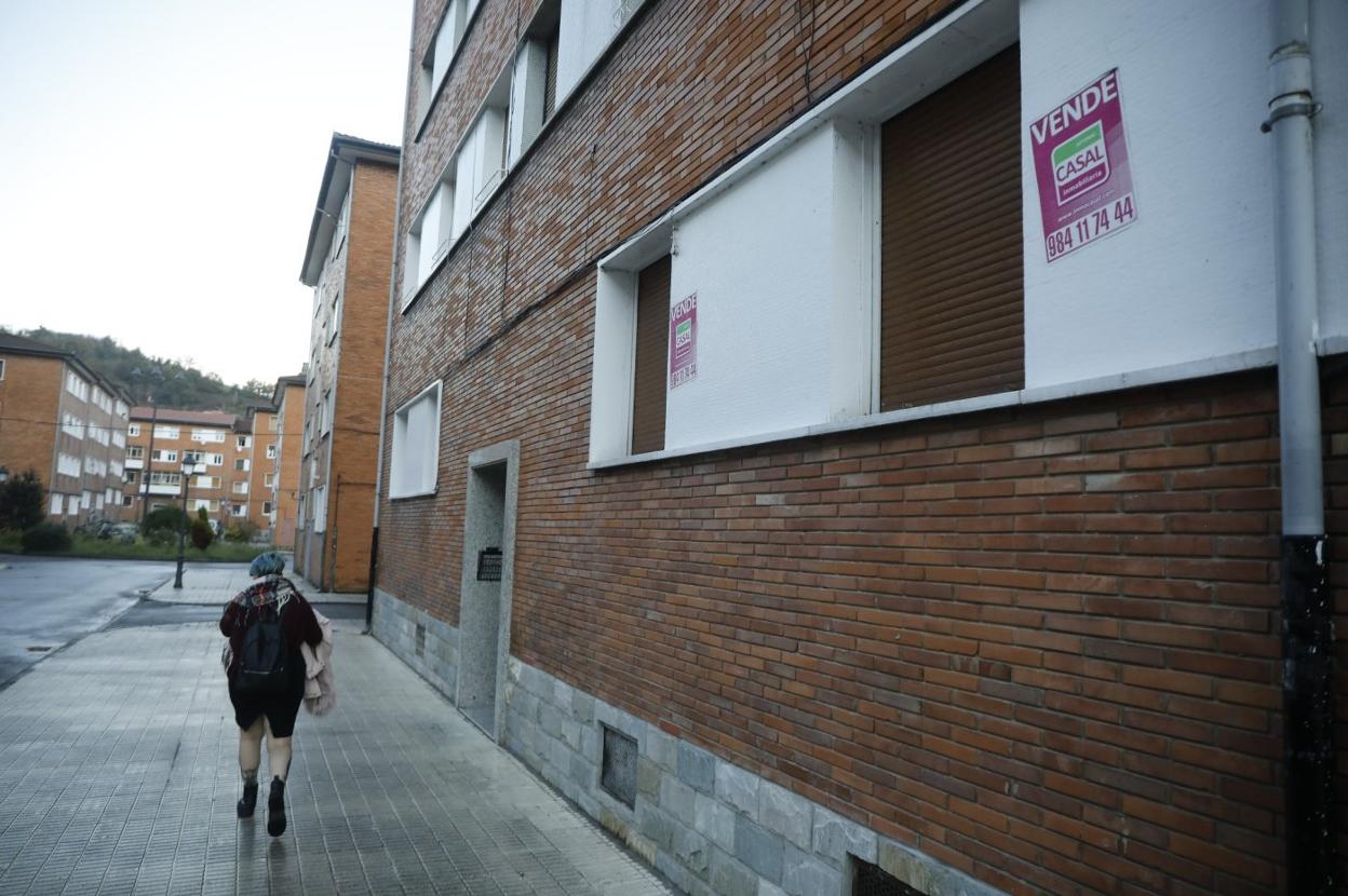 Una joven camina junto a un edificio con pisos en venta en El Serrallo. 