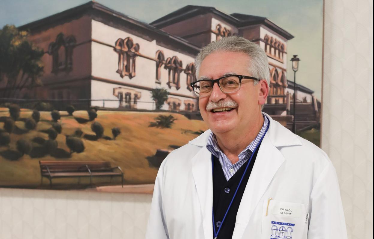 Luis Gago posa delante de un cuadro del Hospital Avilés. 