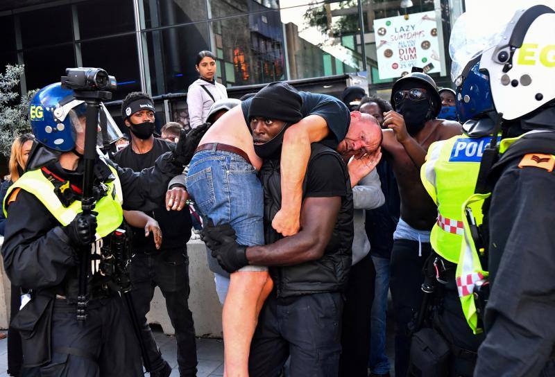 Esta imagen, captada durante una protesta del movimiento 'Black Lives Matter' tras la muerte de George Floyd, muestra al manifestante Patrick Hutchinson llevando a un contramanifestante herido a un lugar seguro, cerca de la estación de Waterloo, en Londres, Gran Bretaña, el 13 de junio de 2020. 