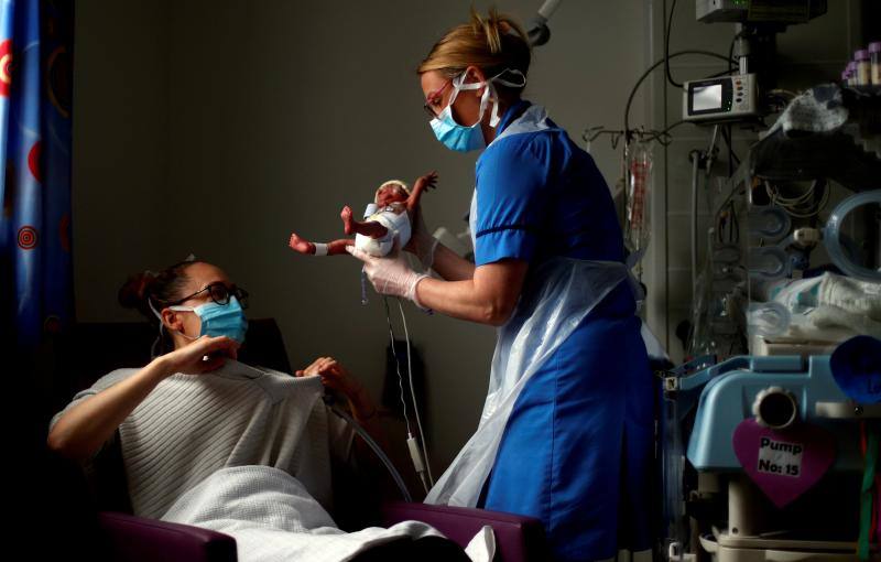 La enfermera Kirsty Hartley entrega al bebé Theo Anderson, que nació de forma prematura, a su madre, Kirsty Anderson, en el Hospital General de Burnley, durante la pandemia de coronavirus. 