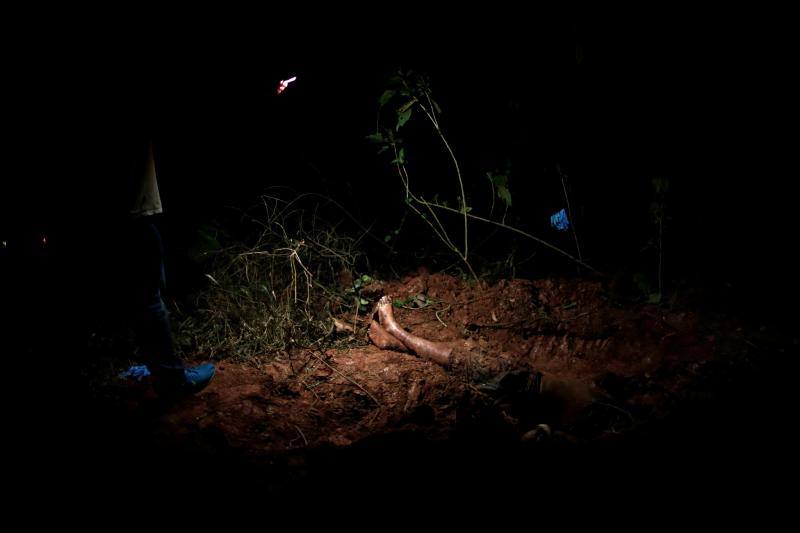 Trabajadores forenses analizan el cuerpo de un hombre asesinado por una facción criminal en un cementerio clandestino durante una operación policial en Sao Paulo, Brasil, el 23 de junio de 2020.