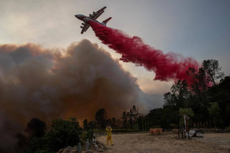 Una mujer con ropa ignífuga fotografía un avión que arroja un líquido rojo para apagar las llamas del grave indencio de Glass, en un viñedo en Deer Park, California, EE.UU. 27 de septiembre de 2020. 