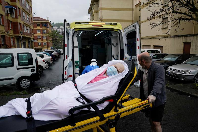 Ander María Dominguez Arias lleva a su madre, María Josefa Arias, de 76 años, enferma de coronavirus, a una ambulancia, con ayuda de la técnica de emergencias Marisa Arguello de Paula. En Llodio, Álava, España, el 19 de abril de 2020. 