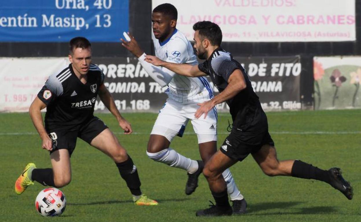 Un jugador del Vetusta trata de zafarse de la presión de dos jugadores del Lealtad.