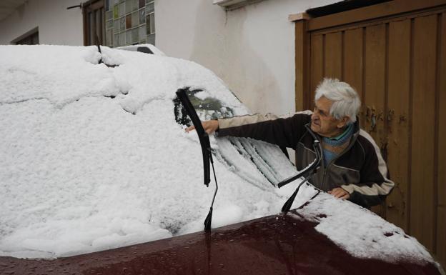 Galería. Un hombre limpia la nieve caída sobre su coche, en Caso.