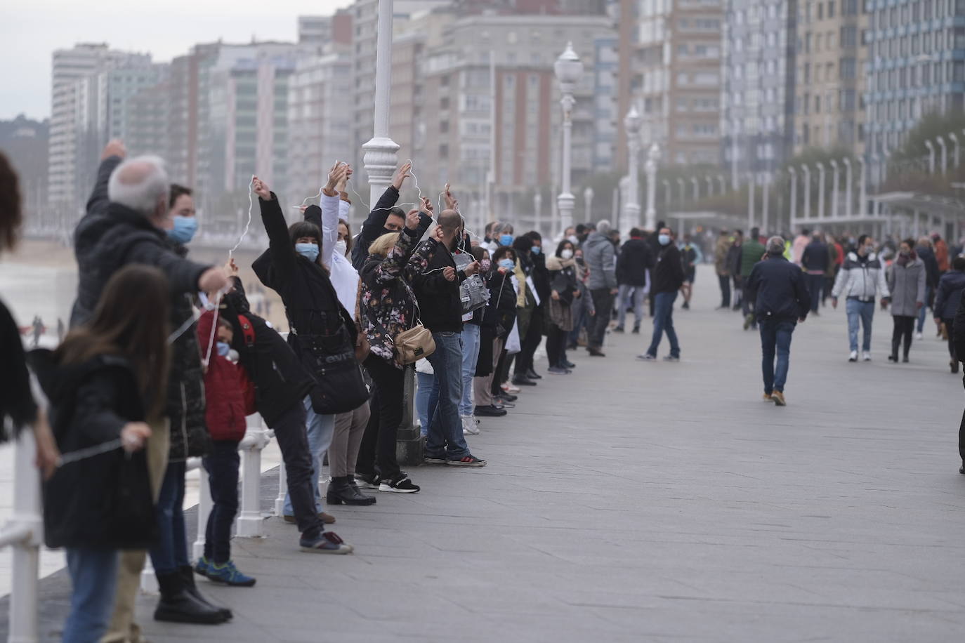 Decenas de personas se han sumado a una cadena humana en el muro de San Lorenzo, en Gijón. Se trata de una iniciativa en defensa de la sanidad pública.