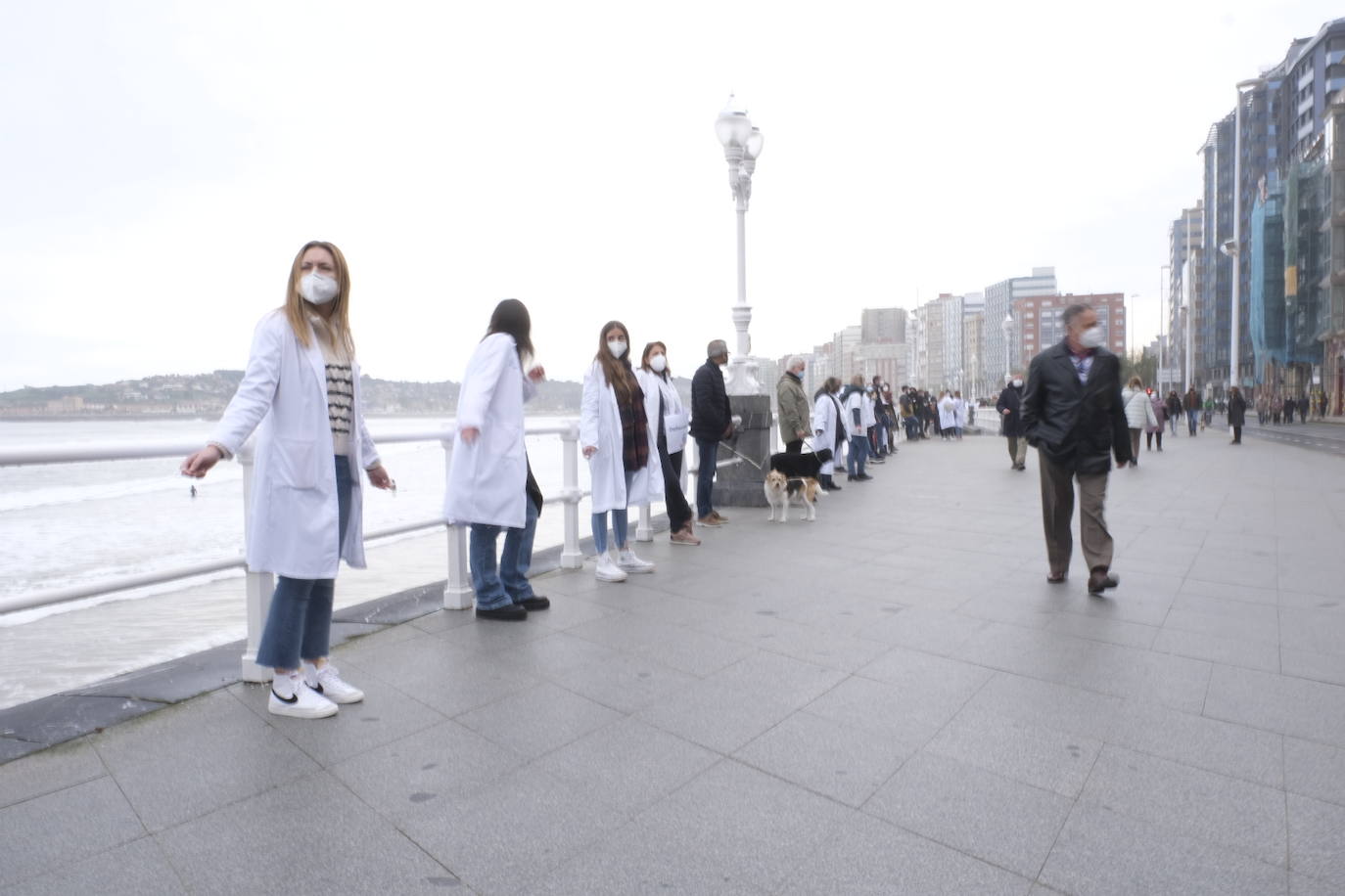 Decenas de personas se han sumado a una cadena humana en el muro de San Lorenzo, en Gijón. Se trata de una iniciativa en defensa de la sanidad pública.