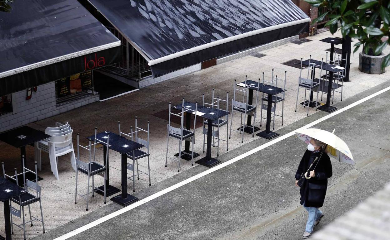Una persona pasea frente a una terraza de Oviedo vacía. 
