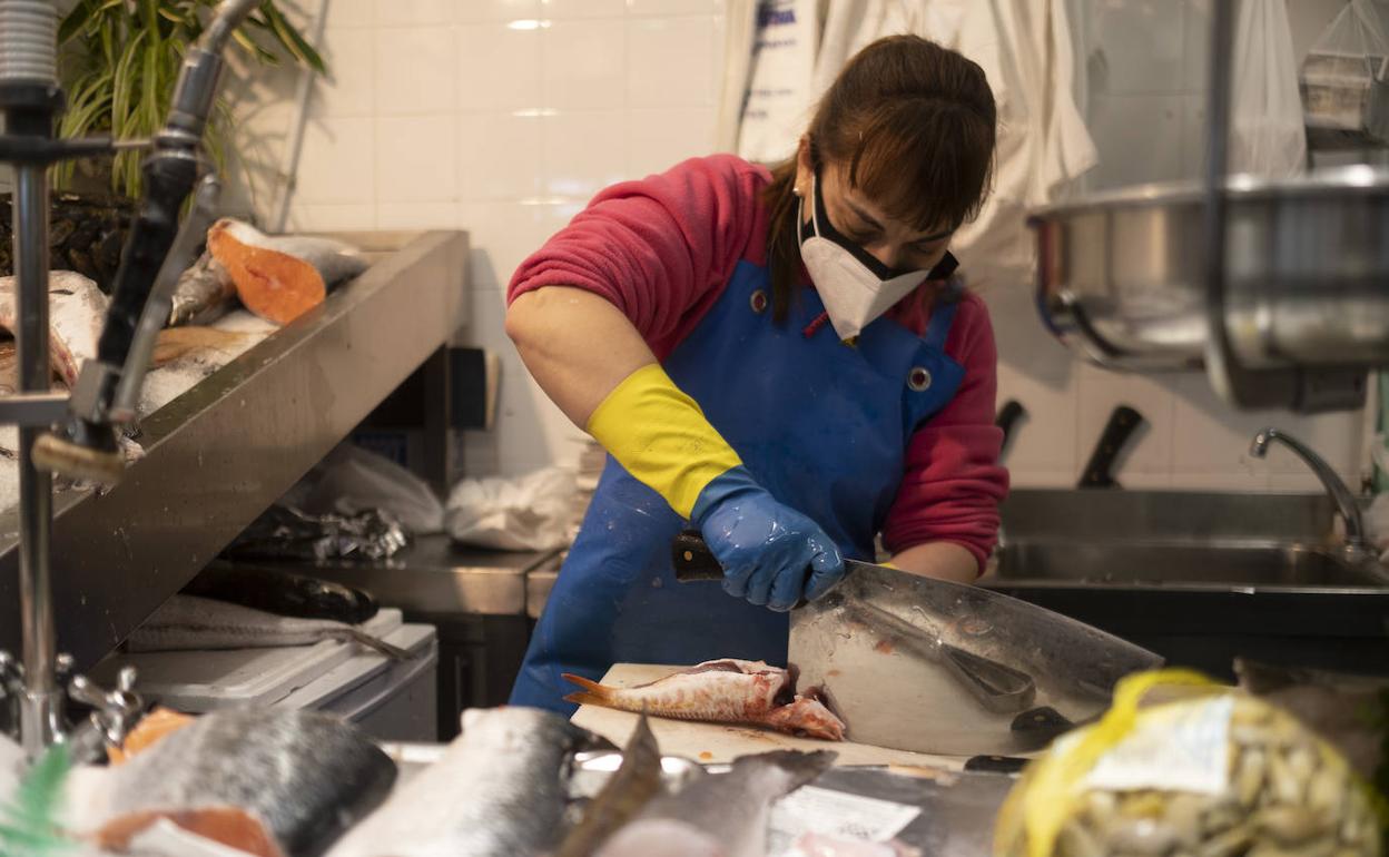 Una trabajadora de Pescados Ana, en el Mercado del Sur, en Gijón, prepara un salmonete.