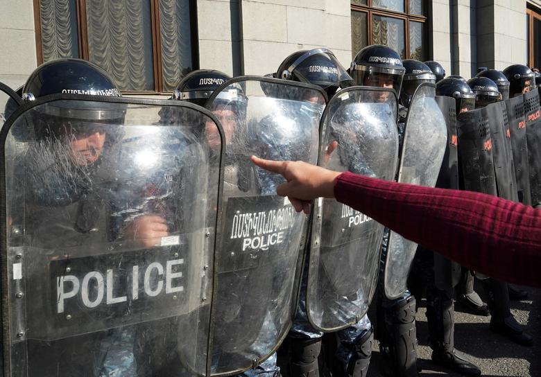 Armenia | Un manifestante hace un gesto hacia los agentes del orden que hacen guardia durante un mitin de la oposición para exigir la renuncia del primer ministro armenio, Nikol Pashinyan, tras la firma del acuerdo para poner fin al conflicto militar en la región de Nagorno-Karabaj, en Ereván, Armenia.