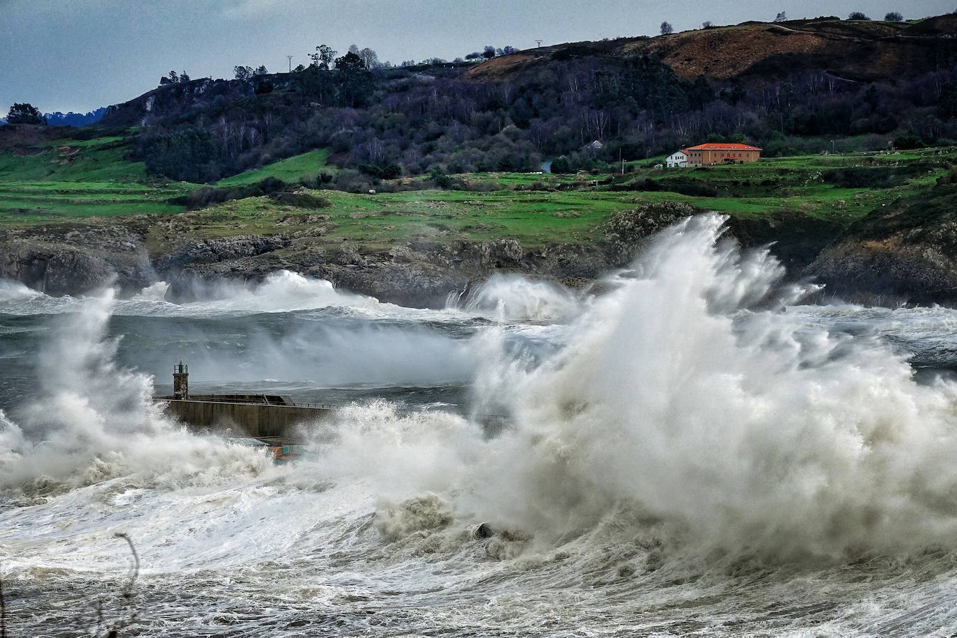 La borrasca 'Bella' ha provocado más de 1.900 incidencias en Asturias y complica las comunicaciones. La nieve acumulada en las últimas horas, que ha cerrado el puerto del Connio, obliga a usar cadenas en 15 altos de montaña. Los fuertes vientos han procovado la caída de árboles y la Aemet mantiene el litoral del Principado en alerta roja por olas de hasta diez metros 