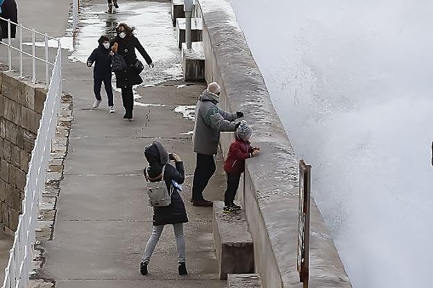 Curiosos viendo el oleaje en el dique de Lequerica, en el Muelle de Gijón. 