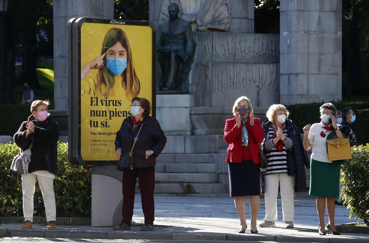 Varias ciudadanas en Oviedo junto a la campaña informativa del Principado que recuerda 'El virus nun piensa, tu sí'. 