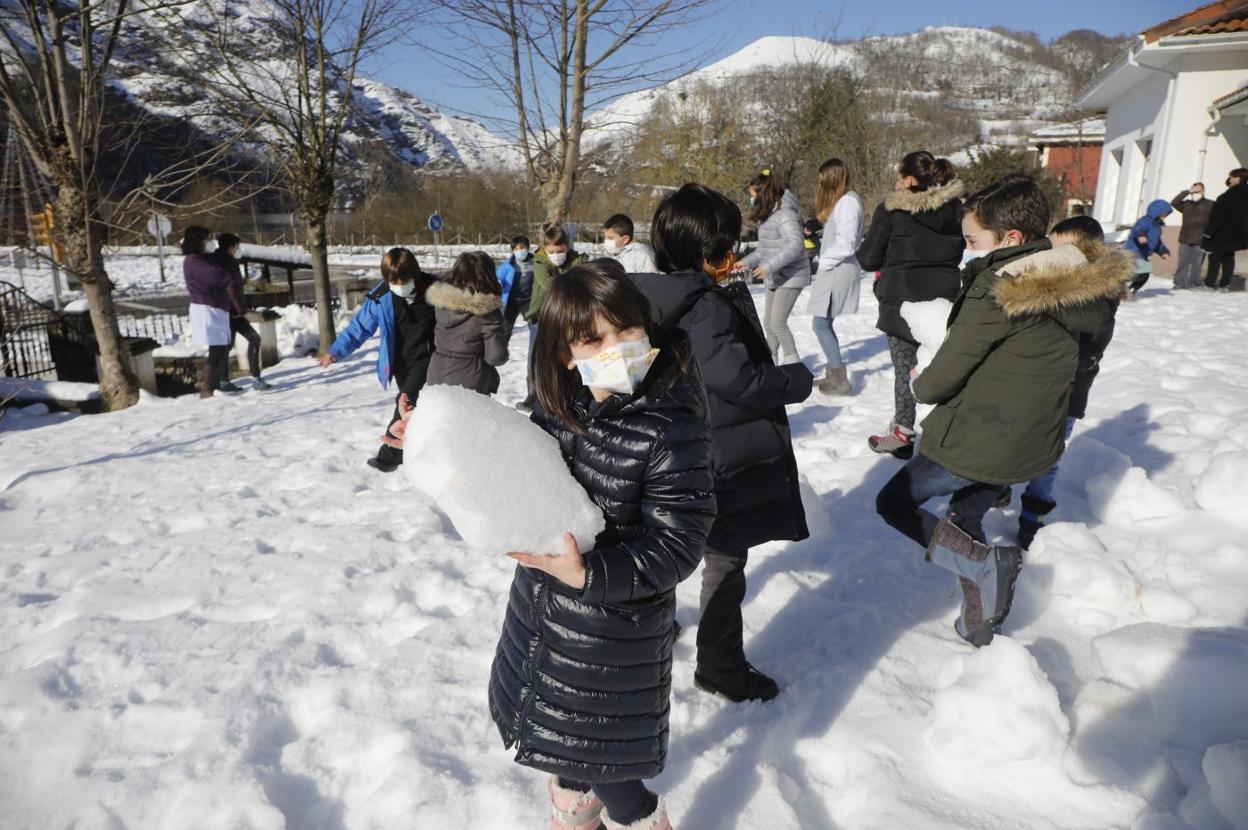 Un grupo de niños juega con la nieve a la entrada del colegio en Rioseco. 