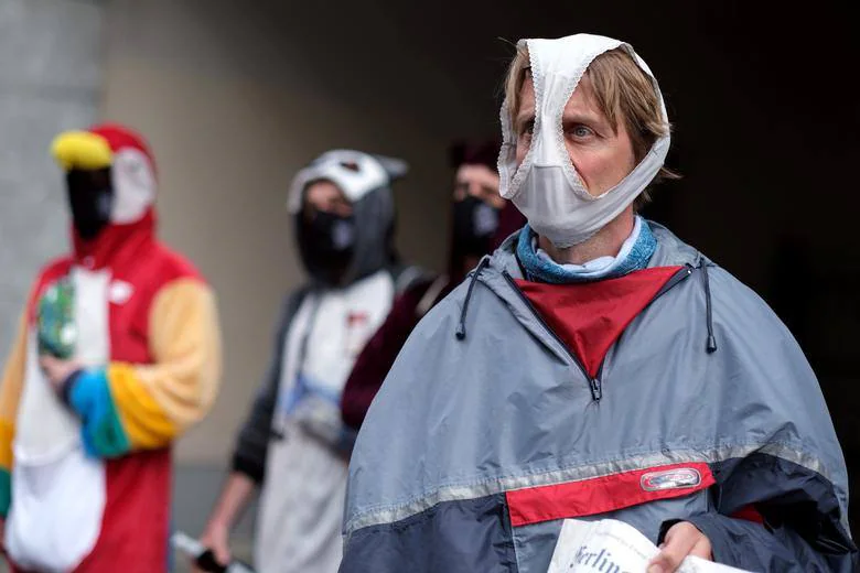 Los manifestantes que cubren sus rostros asisten a una manifestación contra el encierro por coronavirus en Berlín.