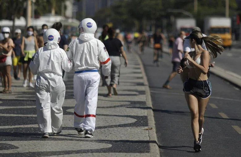 Tercio Galdino, de 66 años, y su esposa Aliceia, de 65, usan sus 'trajes espaciales' protectores mientras caminan por la acera de la playa de Copacabana en medio del brote de coronavirus en Río de Janeiro.
