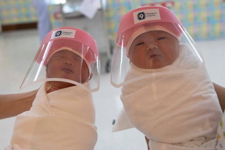 Las enfermeras sostienen a los bebés recién nacidos con protectores faciales en el hospital Praram 9 en Bangkok, Tailandia.