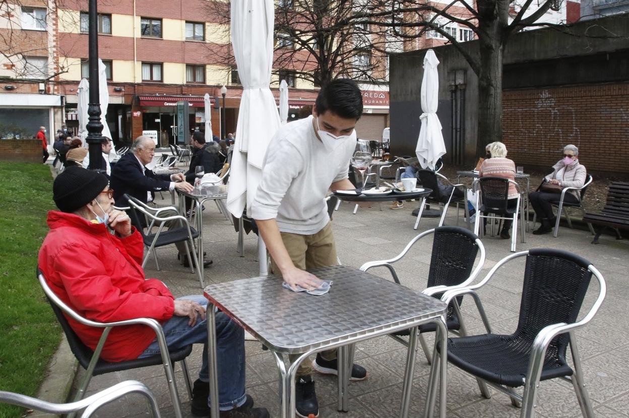 Un camarero limpia una mesa en Gijón. 