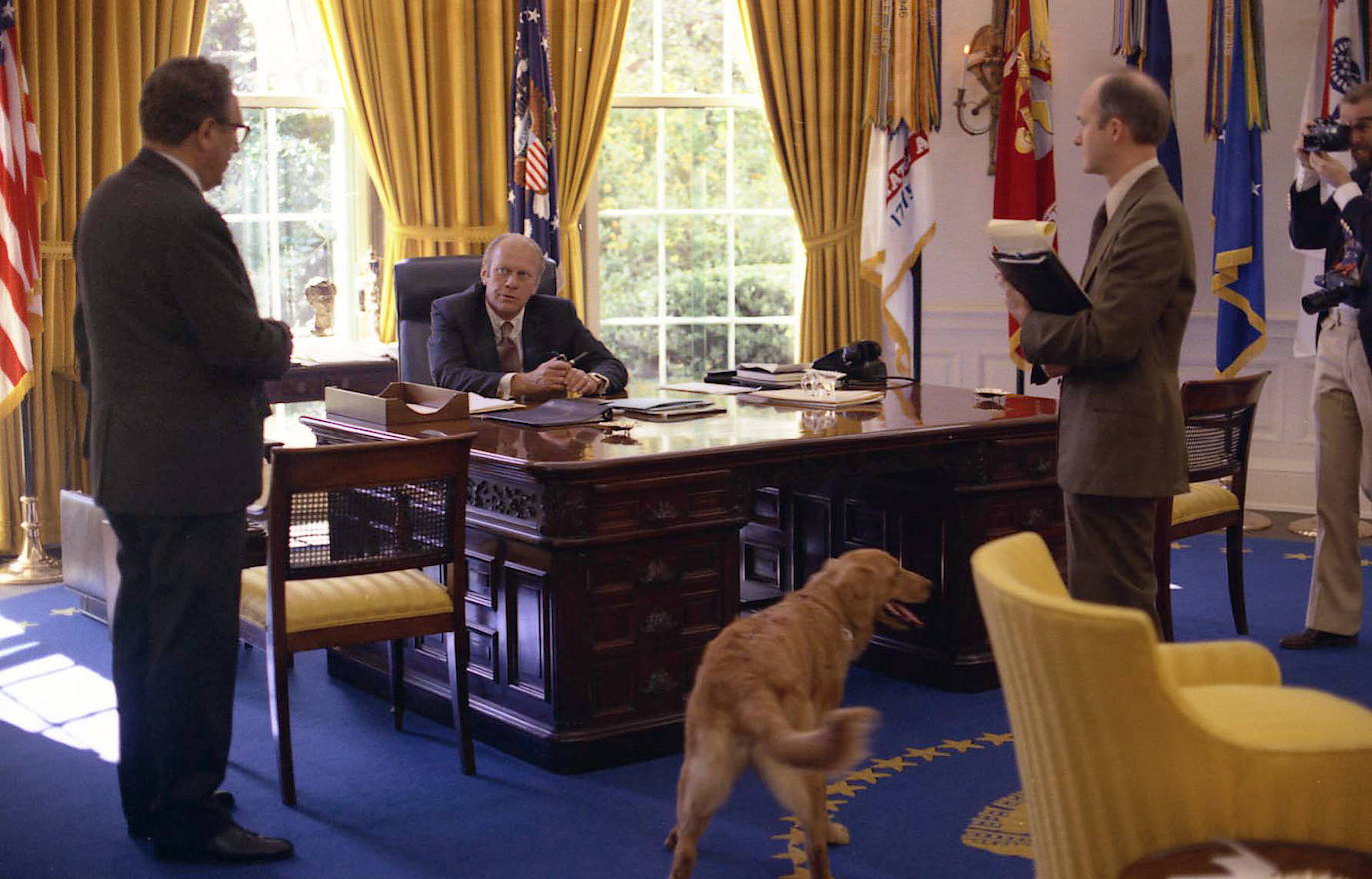 Gerald Ford, en el centro, mientras conversa con el Secretario de Estado Henry Kissinger, a la izquierda, y el Asesor de Seguridad Nacional Brent Scowcroft en el Despacho Oval de la Casa Blanca en Washington. Su perro Liberty, un golden retriever de Ford, aparece en primer plano.