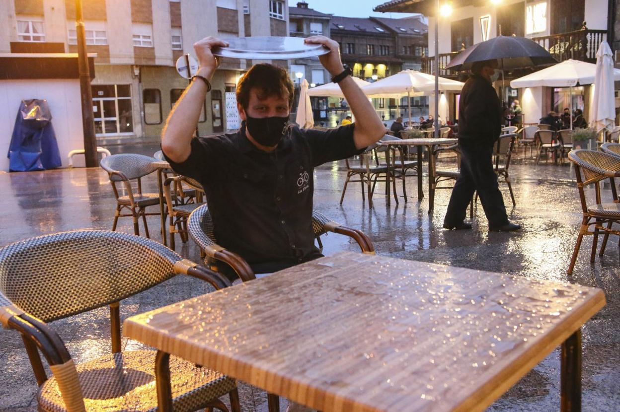 Con humor, Rufino Riestra se protege de la lluvia con la bandeja en el bar La Flaca de la Pola. 