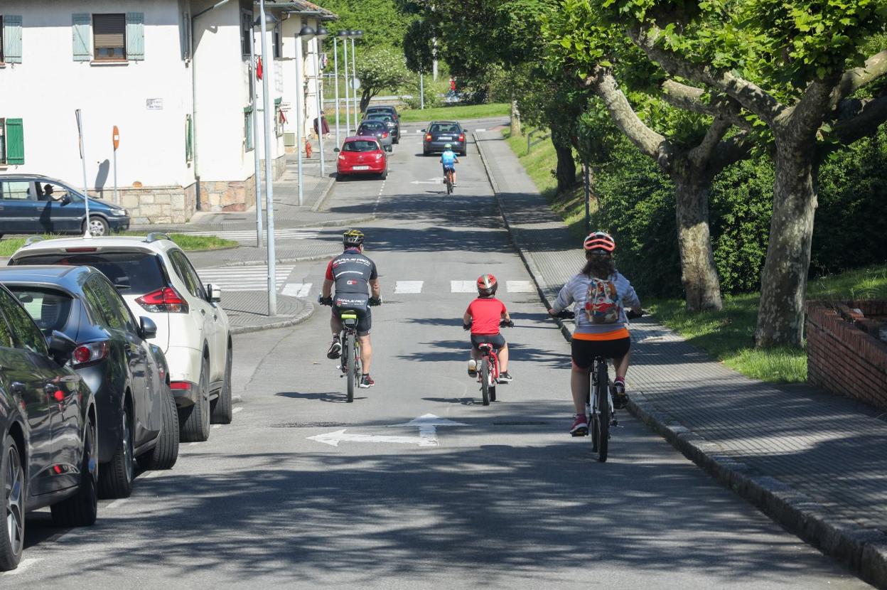 Una familia transita en bici por el poblado de Llaranes. 