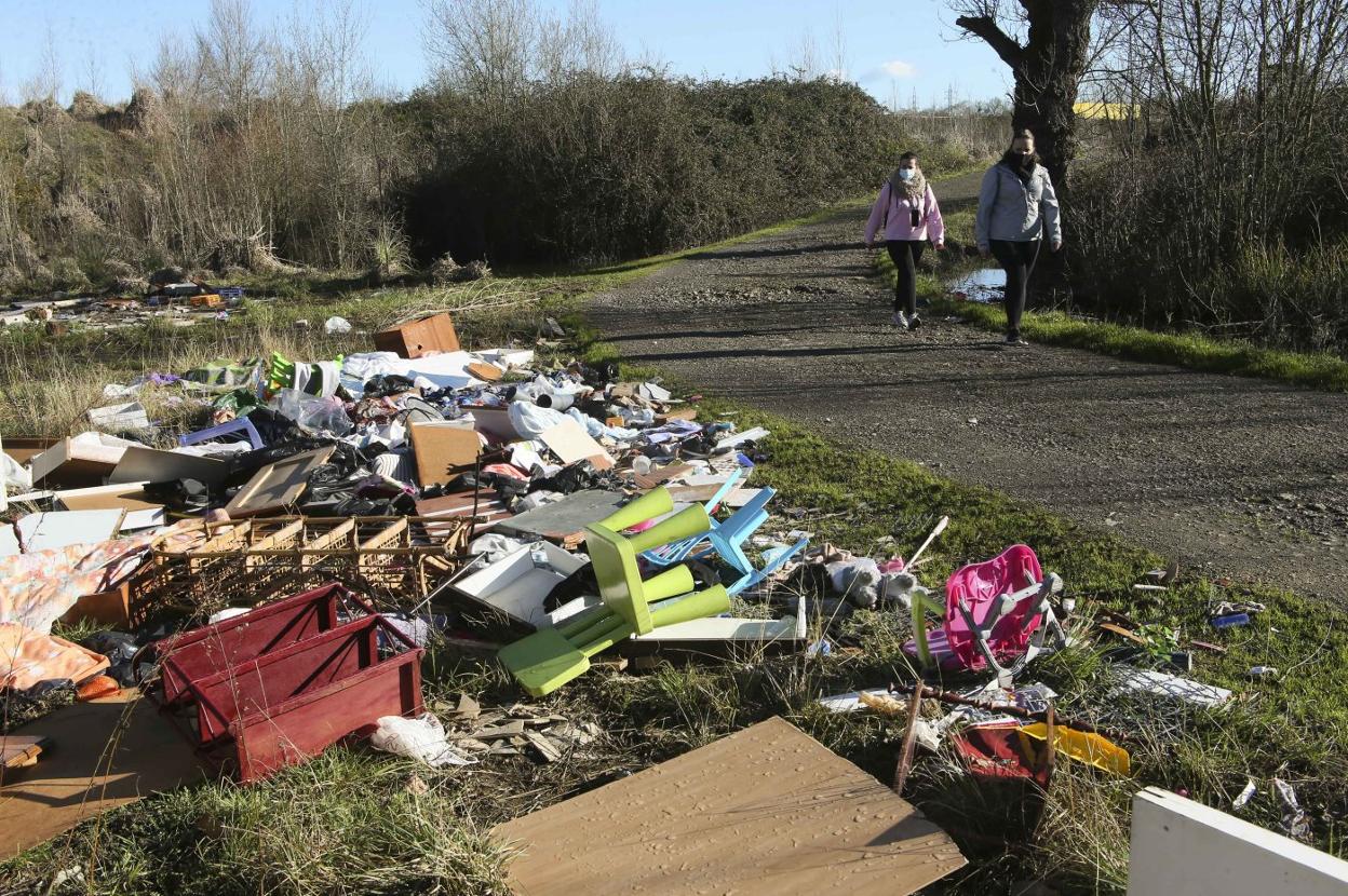 Dos personas pasean por la senda que une Lugones con Llanera. 
