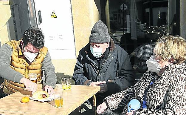 A la derecha Juan Riestra corta un bollo con su padre y su tía. 