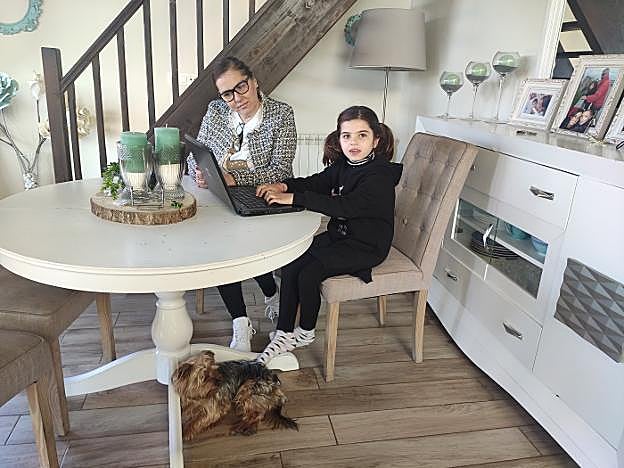 Ángela Álvarez, ante el ordenador, con su hija Adriana y su perro 'Caco'. 