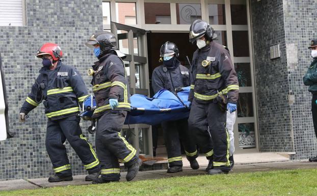 Efectivos de Bomberos sacan uno de los dos cuerpos del bloque de viviendas de Villaviciosa afectado por un incendio.