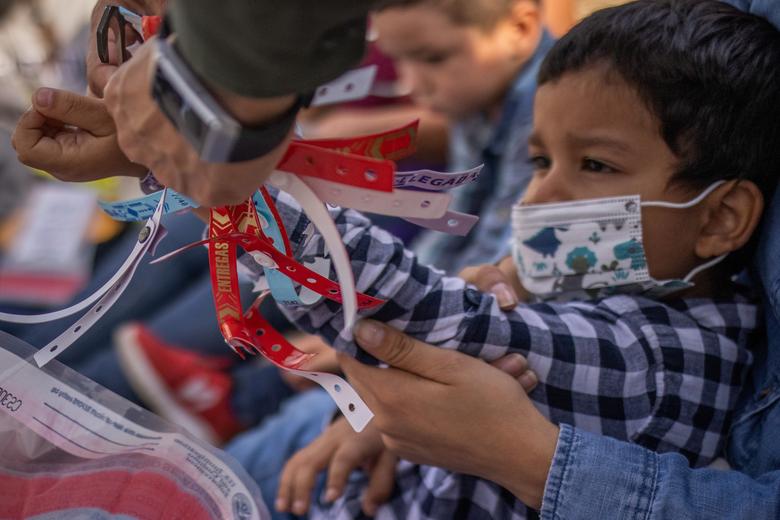 Un agente de la Patrulla Fronteriza de los EE. UU. Se quita una pulsera que llevaba Santiago, un niño migrante hondureño de cuatro años que solicita asilo, después de que cruzó el río Grande hacia Estados Unidos desde México con su madre.